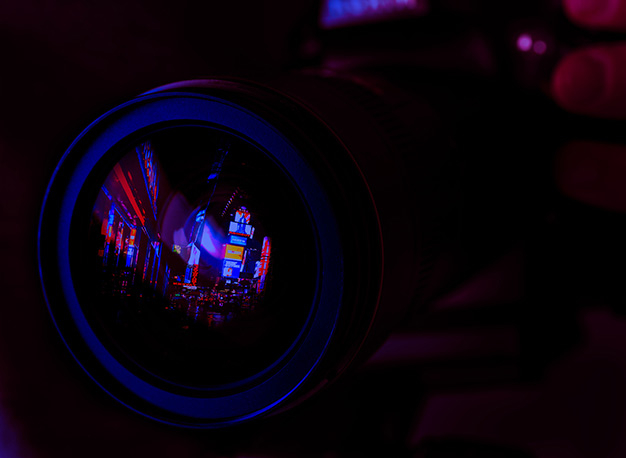 Neonlichter spiegeln sich in einer Kameralinse